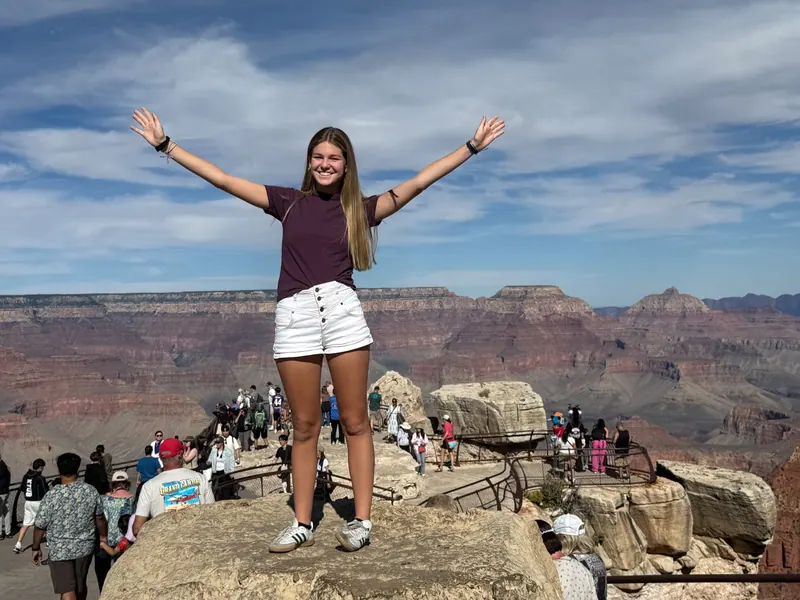 A young traveler smiling with arms outstretched at a canyon overlook