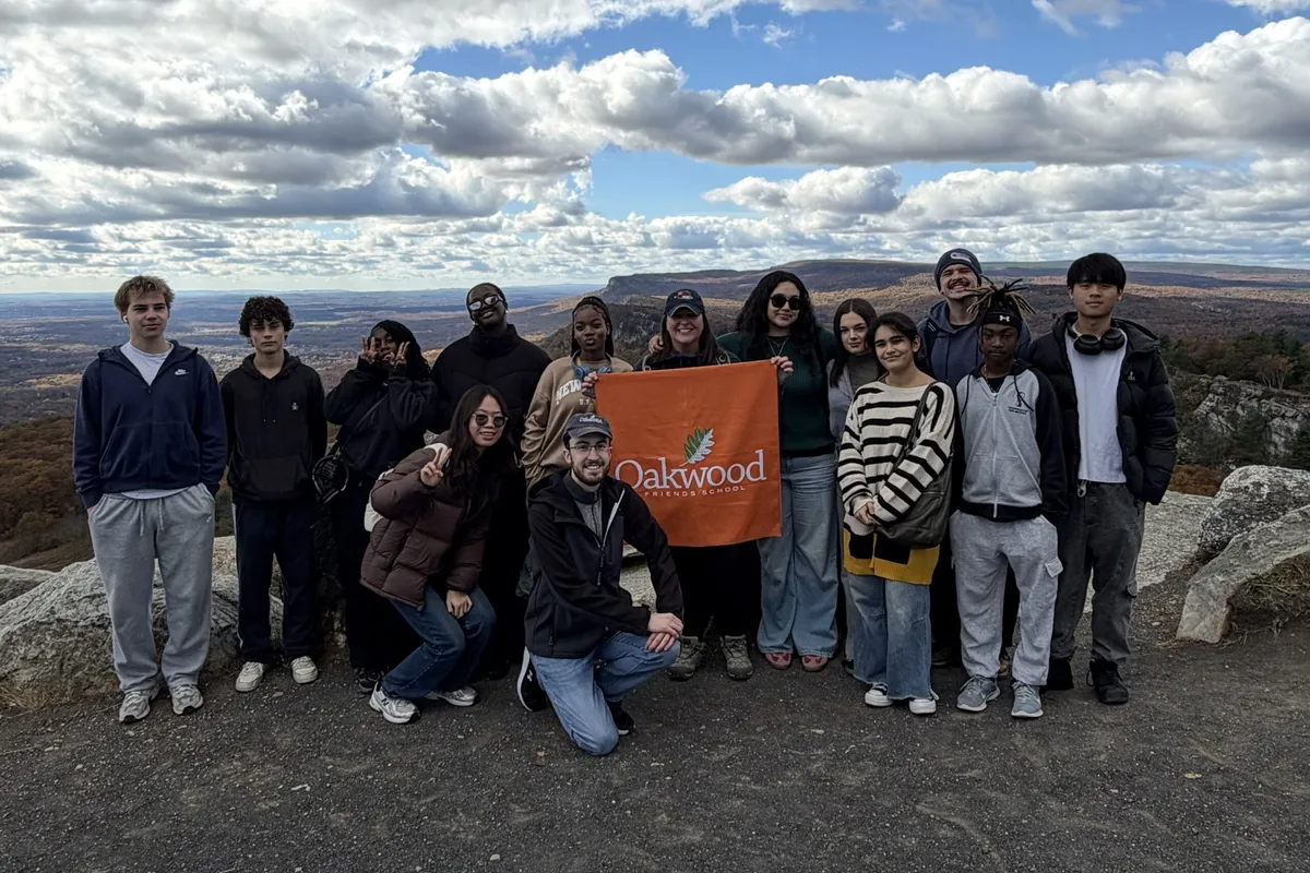 An Oakwood Friends group holding the school banner at a scenic overlook